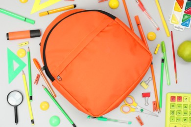 Backpack and different school supplies on light gray background, flat lay