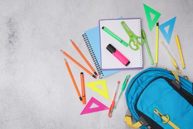 Photo of Flat lay composition with backpack and different school stationery on light grey table, space for text