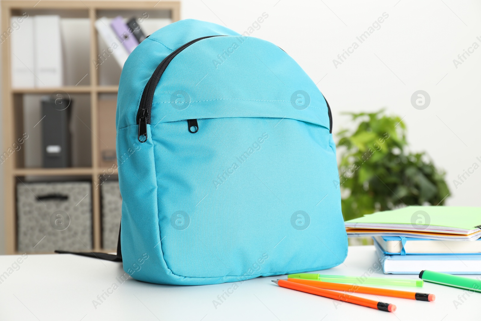 Photo of Backpack and different school stationery on white table indoors