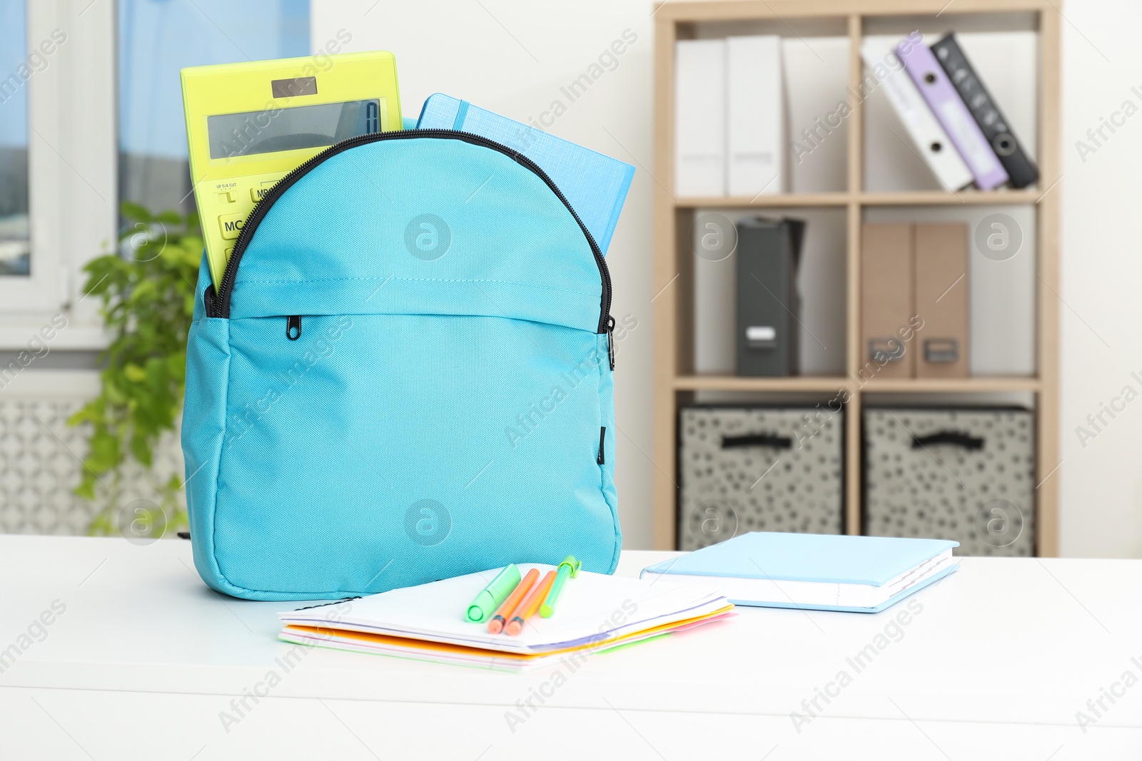 Photo of Backpack and different school stationery on white table indoors