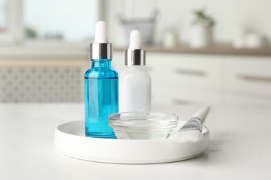 Photo of Peeling procedure. Bottles of chemical peel, bowl with liquid and brush on white table indoors