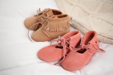 Photo of Twins concept. Two pairs of baby shoes on bed, closeup