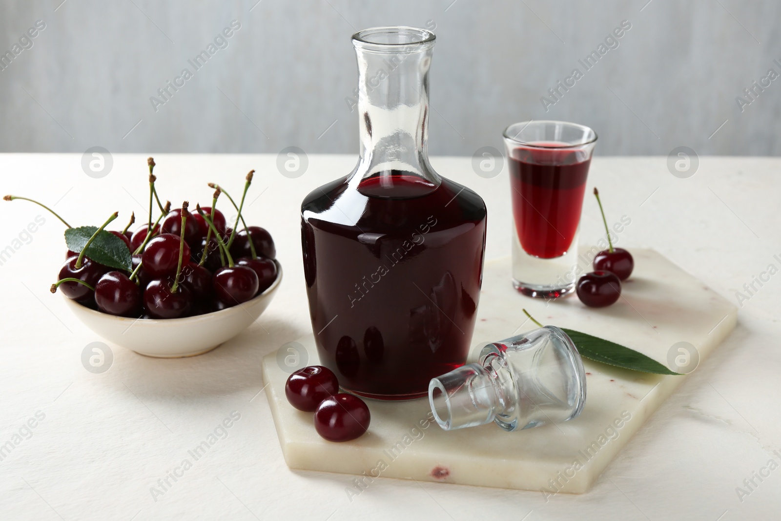 Photo of Delicious cherry liqueur and berries on white table