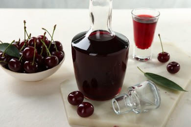 Photo of Delicious cherry liqueur and berries on white table