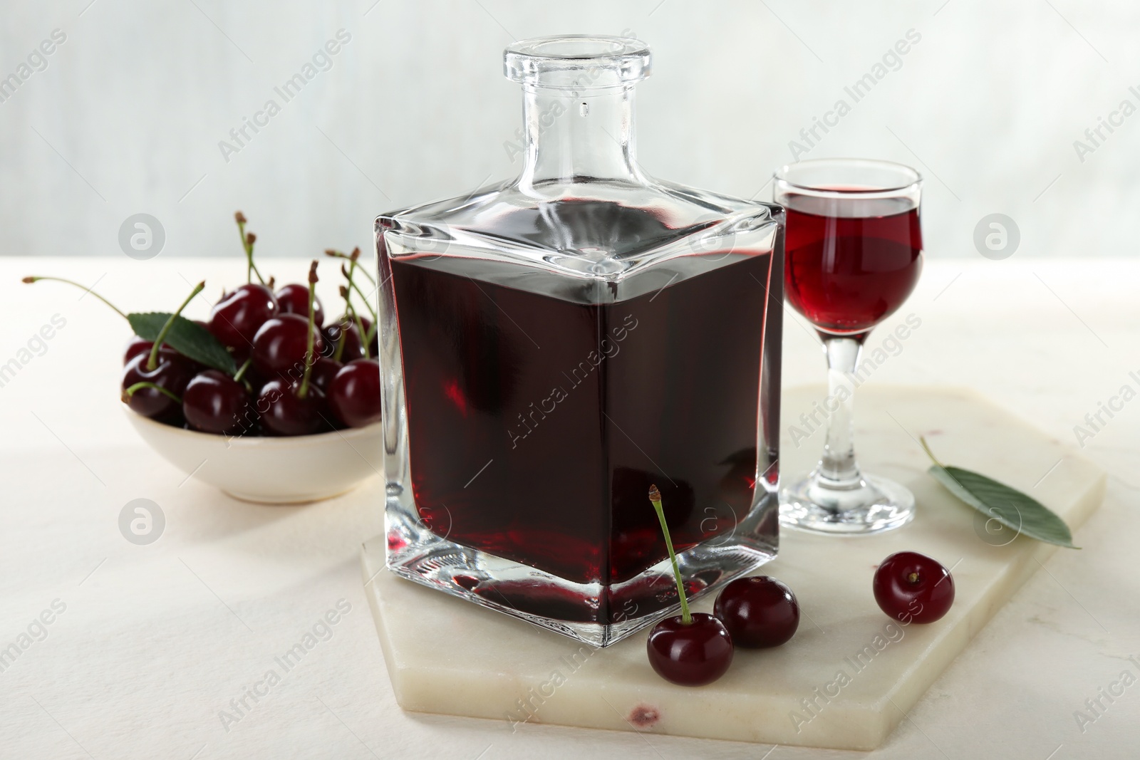 Photo of Delicious cherry liqueur and berries on white table