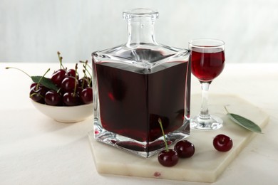 Delicious cherry liqueur and berries on white table