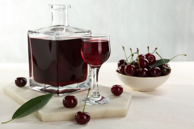 Photo of Delicious cherry liqueur and berries on white table