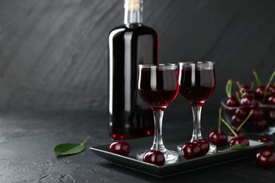 Photo of Delicious cherry liqueur and berries on black table