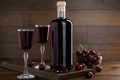 Photo of Delicious cherry liqueur and berries on wooden table