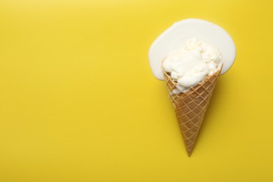 Photo of Melted ice cream in wafer cone on yellow background, top view. Space for text