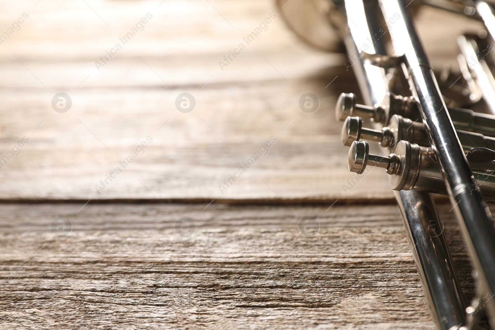 Photo of One trumpet on wooden table, closeup. Space for text