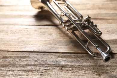 One trumpet on wooden table, closeup. Space for text