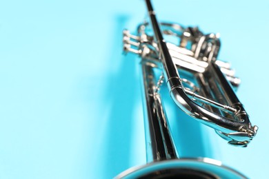 Photo of One trumpet on light blue background, closeup. Space for text