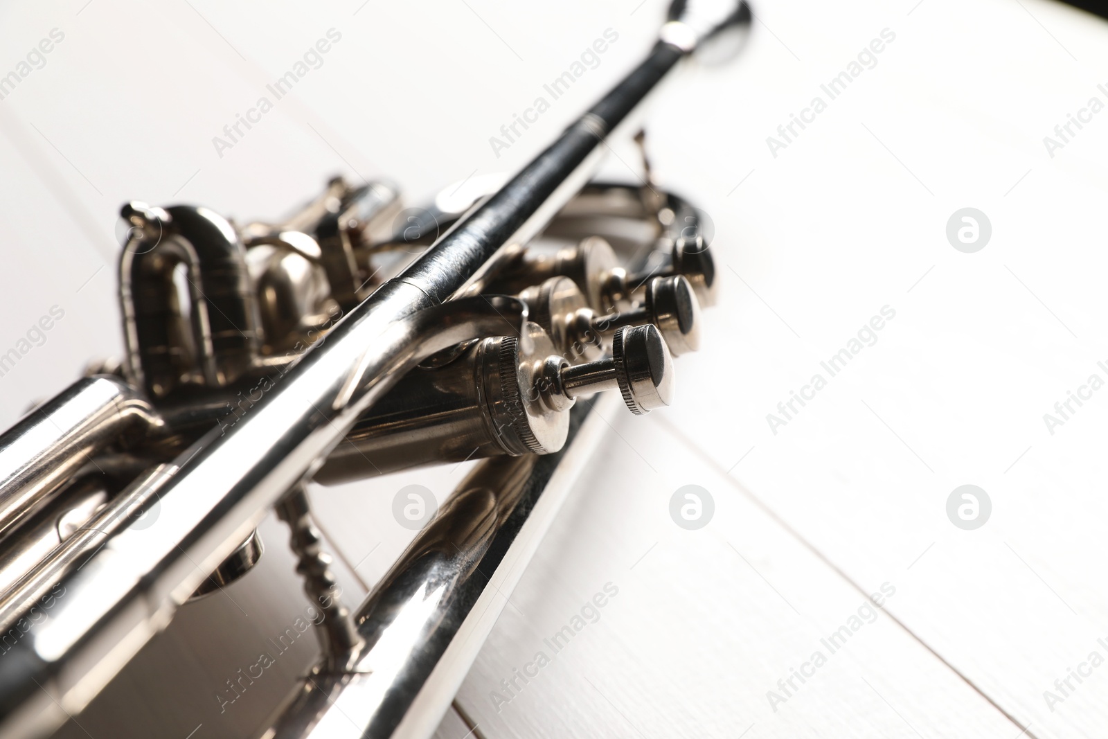 Photo of One trumpet on white wooden table, closeup. Space for text