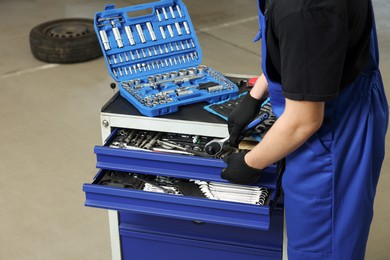 Auto mechanic with different tools at automobile repair shop, closeup