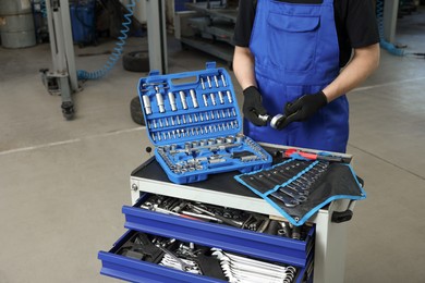 Auto mechanic with different tools at automobile repair shop, closeup