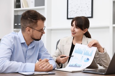 Photo of Smiling consultant working with client at table in office. Business meeting