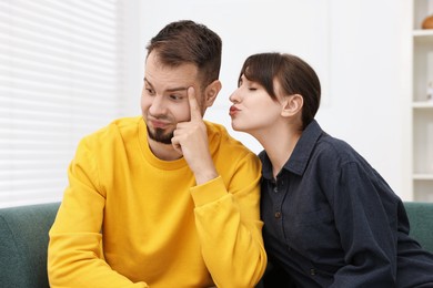 Woman trying to kiss embarrassed man at home