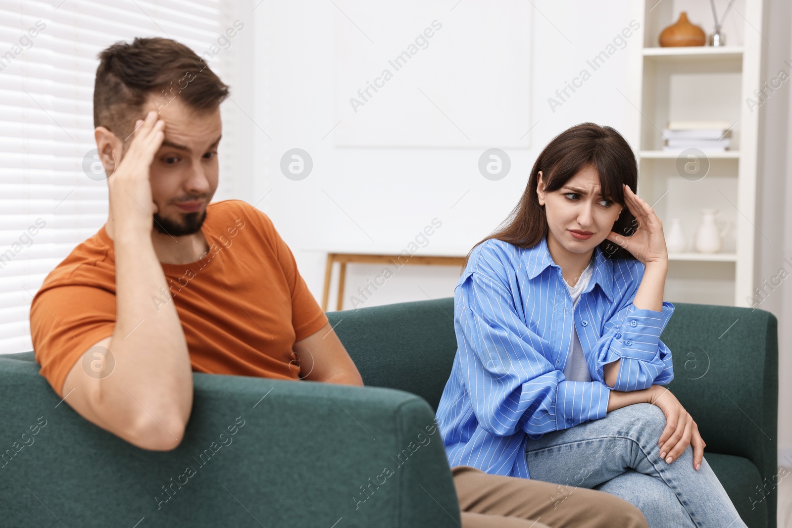 Photo of Embarrassed couple ignoring each other on sofa at home