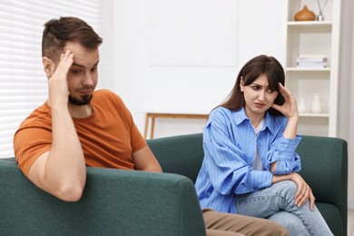 Photo of Embarrassed couple ignoring each other on sofa at home