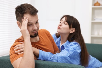 Woman trying to kiss embarrassed man at home