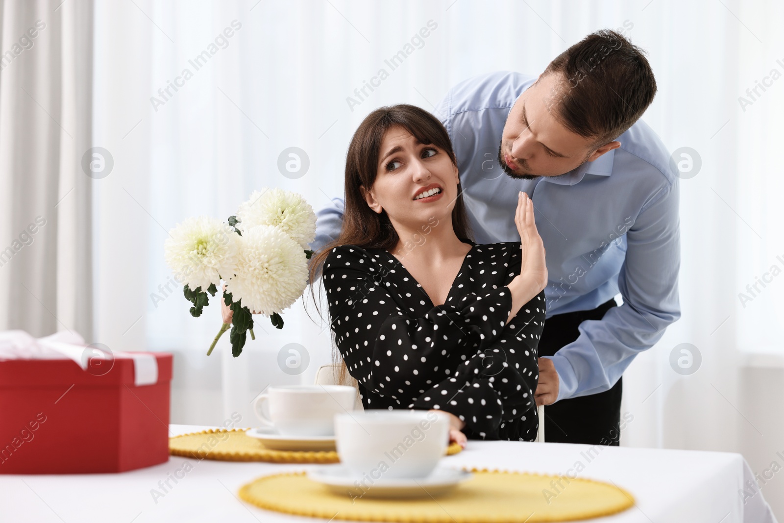 Photo of Bad date. Embarrassed woman refusing from man's kiss indoors