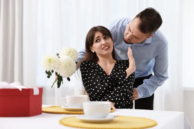 Bad date. Embarrassed woman refusing from man's kiss indoors