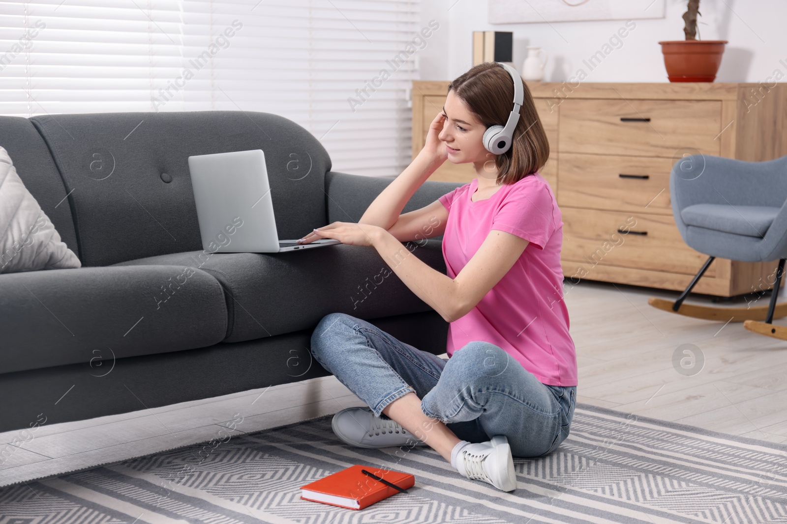 Photo of Teenager in headphones working with laptop at home. Remote job