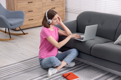 Photo of Teenager in headphones working with laptop at home. Remote job