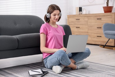 Teenager in headphones working with laptop at home. Remote job