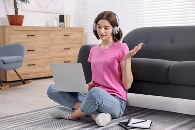 Teenager in headphones having video chat via laptop at home. Remote work