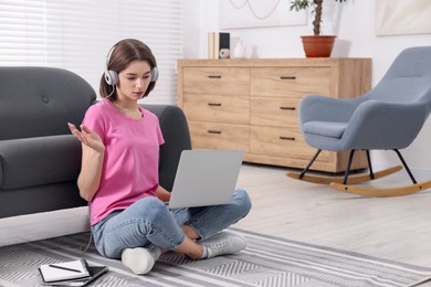 Teenager in headphones having video chat via laptop at home. Remote work