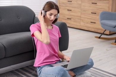 Teenager in headphones working with laptop at home. Remote job