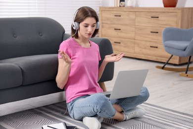 Teenager in headphones having video chat via laptop at home. Remote work