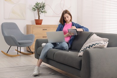 Teenager taking notes while working with laptop at home. Remote job