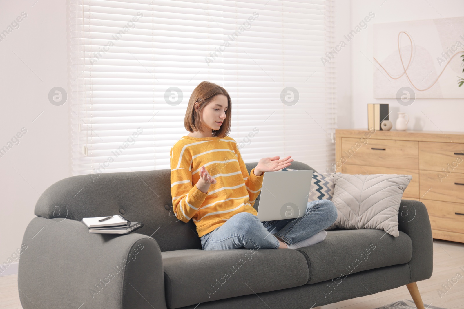 Photo of Teenager having video chat via laptop at home. Remote work