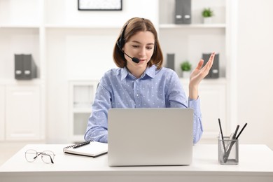 Teenager in headset having video chat via laptop at home. Remote work