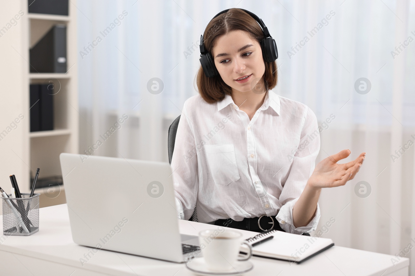 Photo of Teenager in headset having video chat via laptop at home. Remote work