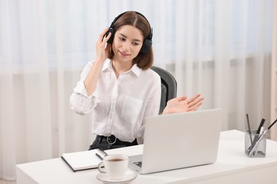 Teenager in headset having video chat via laptop at home. Remote work