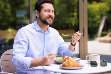 Happy man having breakfast in outdoor cafe