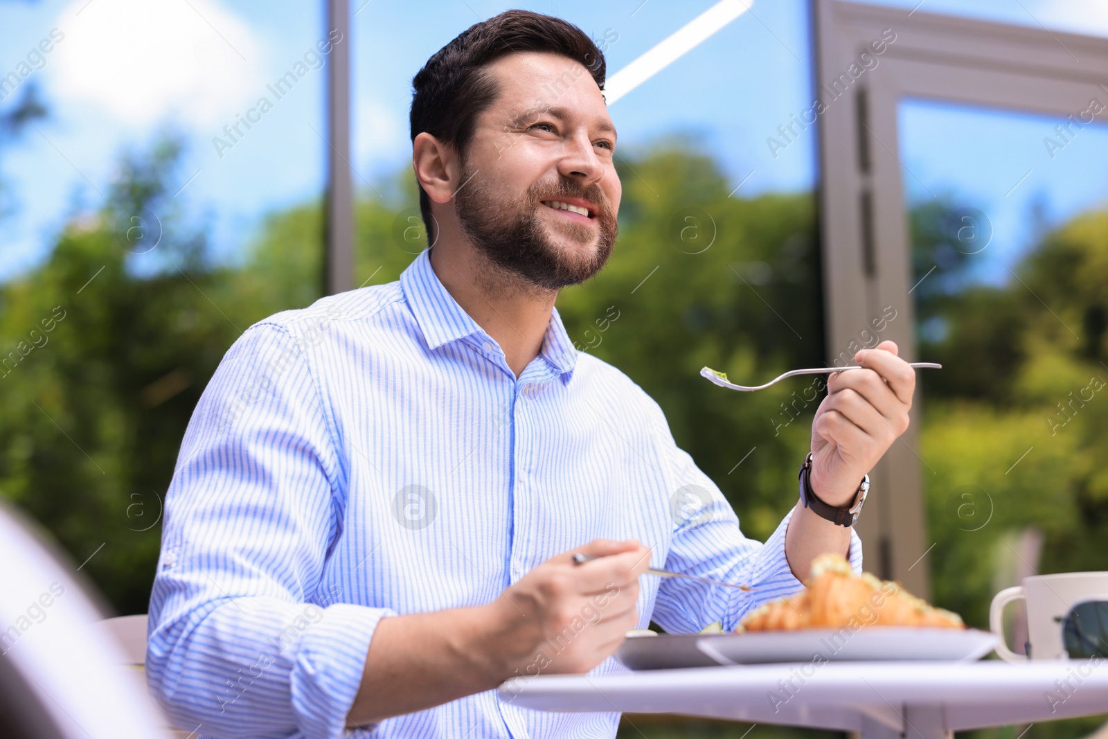 Photo of Happy man having breakfast in outdoor cafe