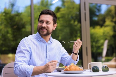 Happy man having breakfast in outdoor cafe