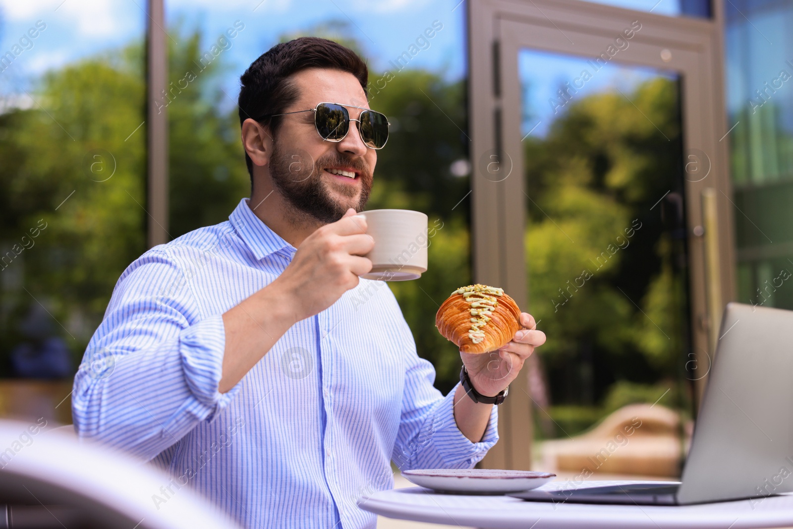 Photo of Happy man having breakfast in outdoor cafe