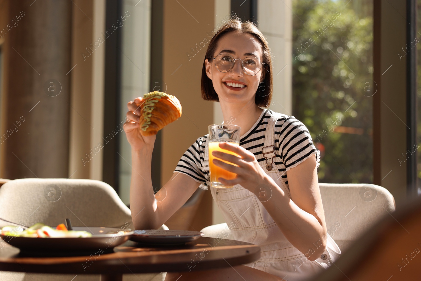 Photo of Happy woman having tasty breakfast in cafe