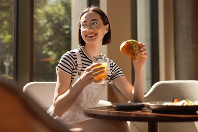 Photo of Happy woman having tasty breakfast in cafe