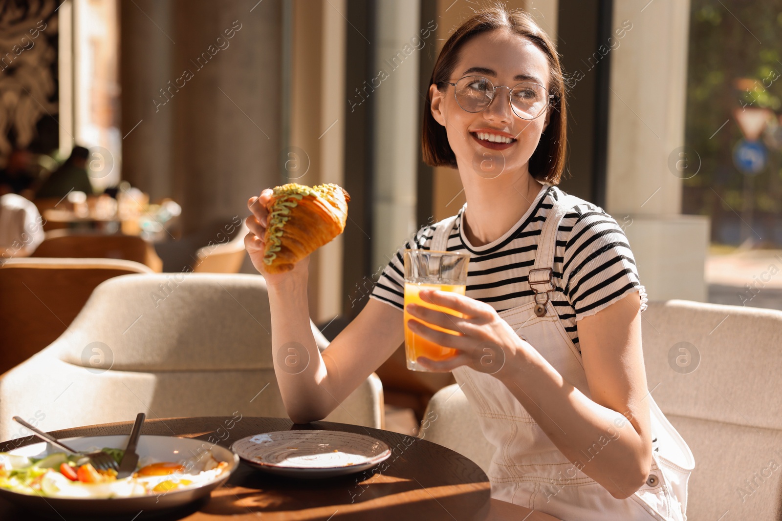 Photo of Happy woman having tasty breakfast in cafe