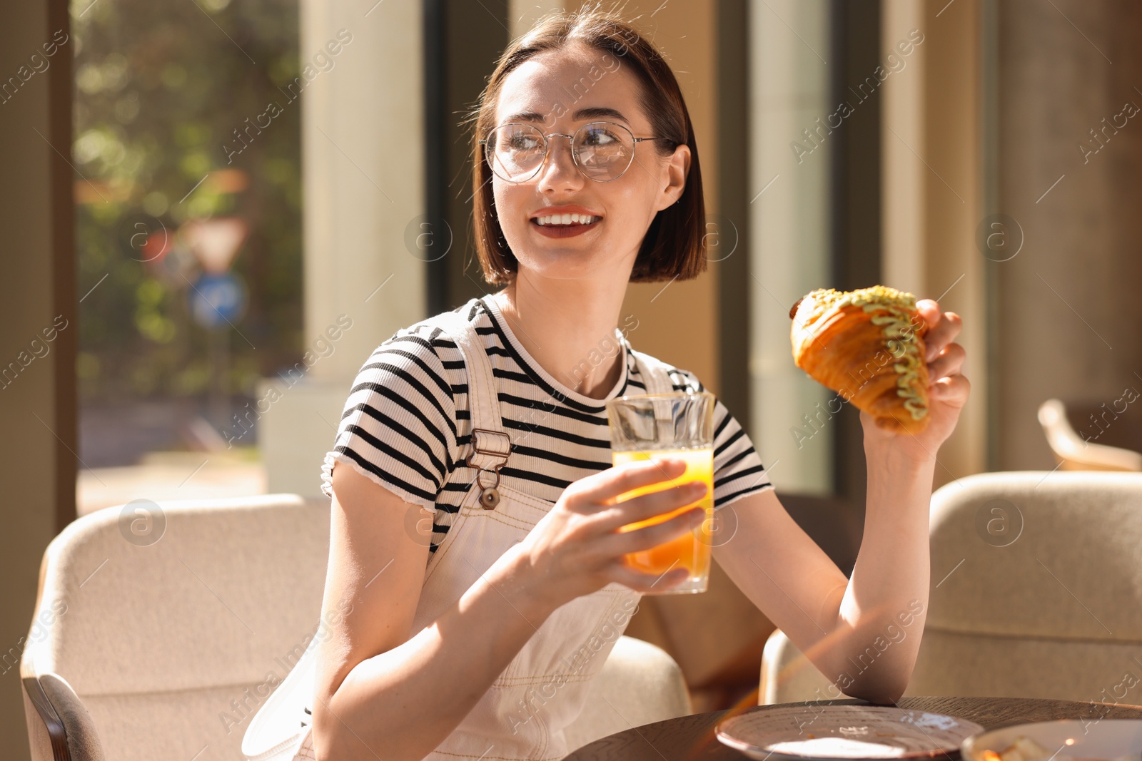 Photo of Happy woman having tasty breakfast in cafe