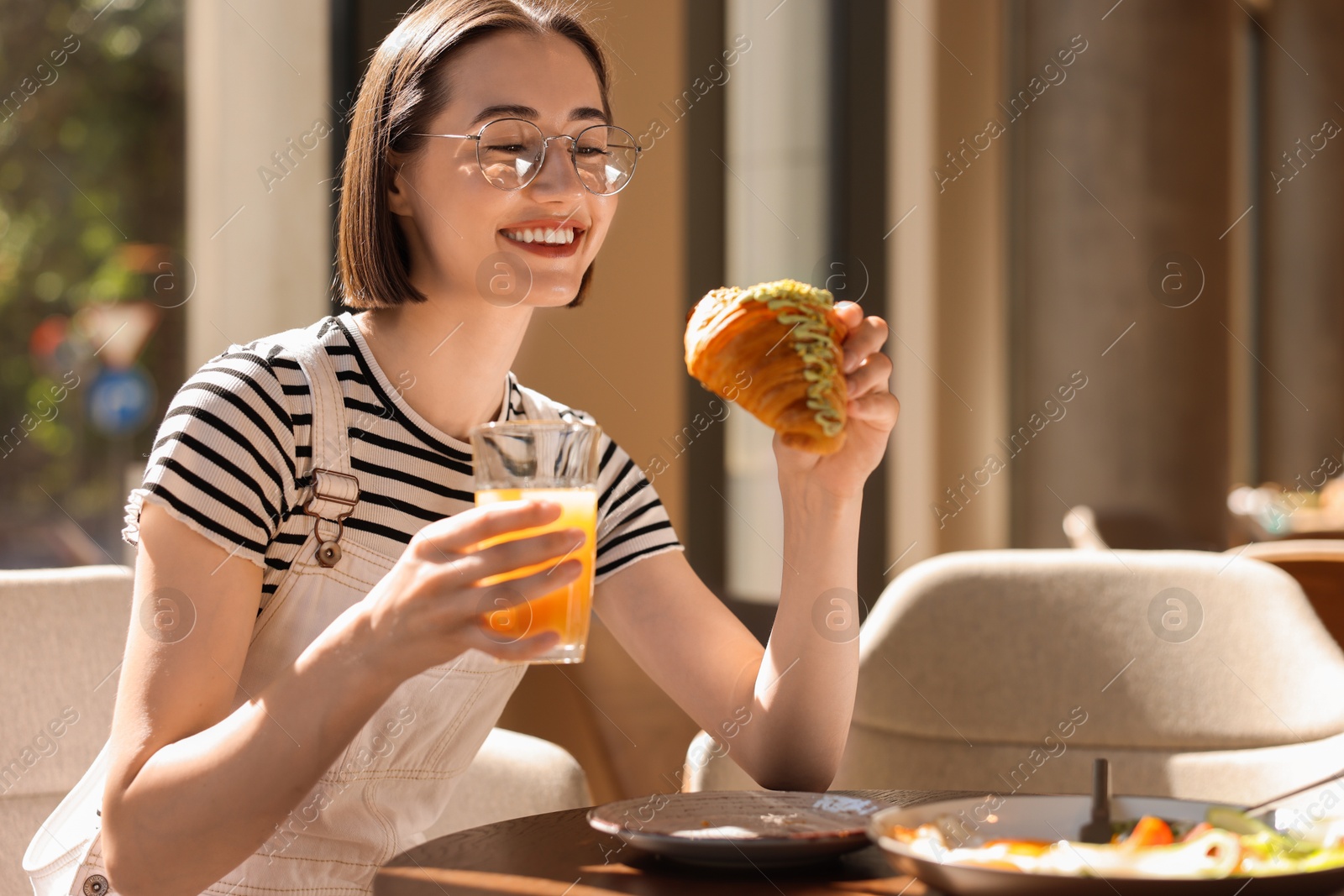 Photo of Happy woman having tasty breakfast in cafe