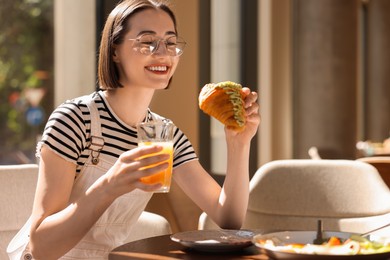 Photo of Happy woman having tasty breakfast in cafe