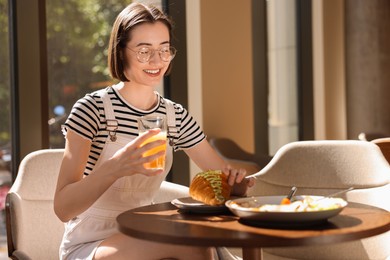 Photo of Happy woman having tasty breakfast in cafe